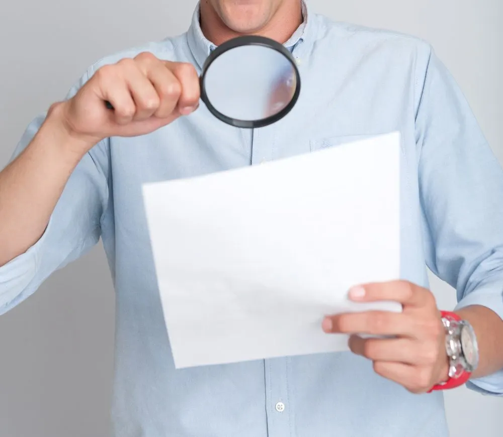 decorative. Man holding magnifying glass up to see paper.